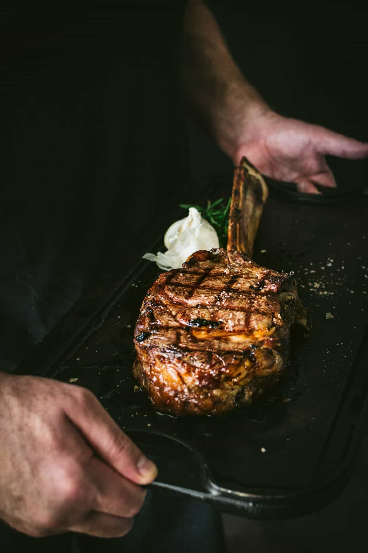 Man holding Tomahawk Steak on Cast Iron Griddle 