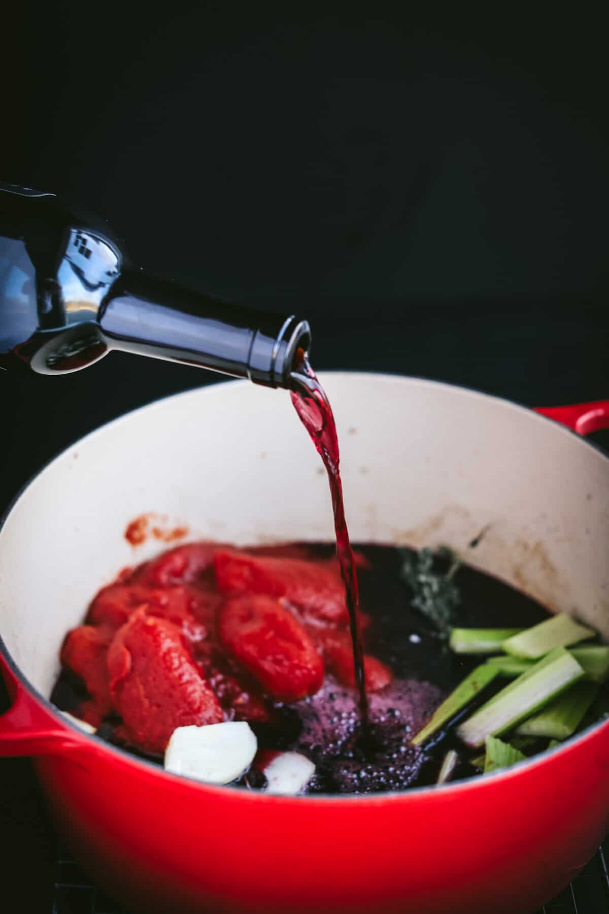 Red wine being poured into dutch oven