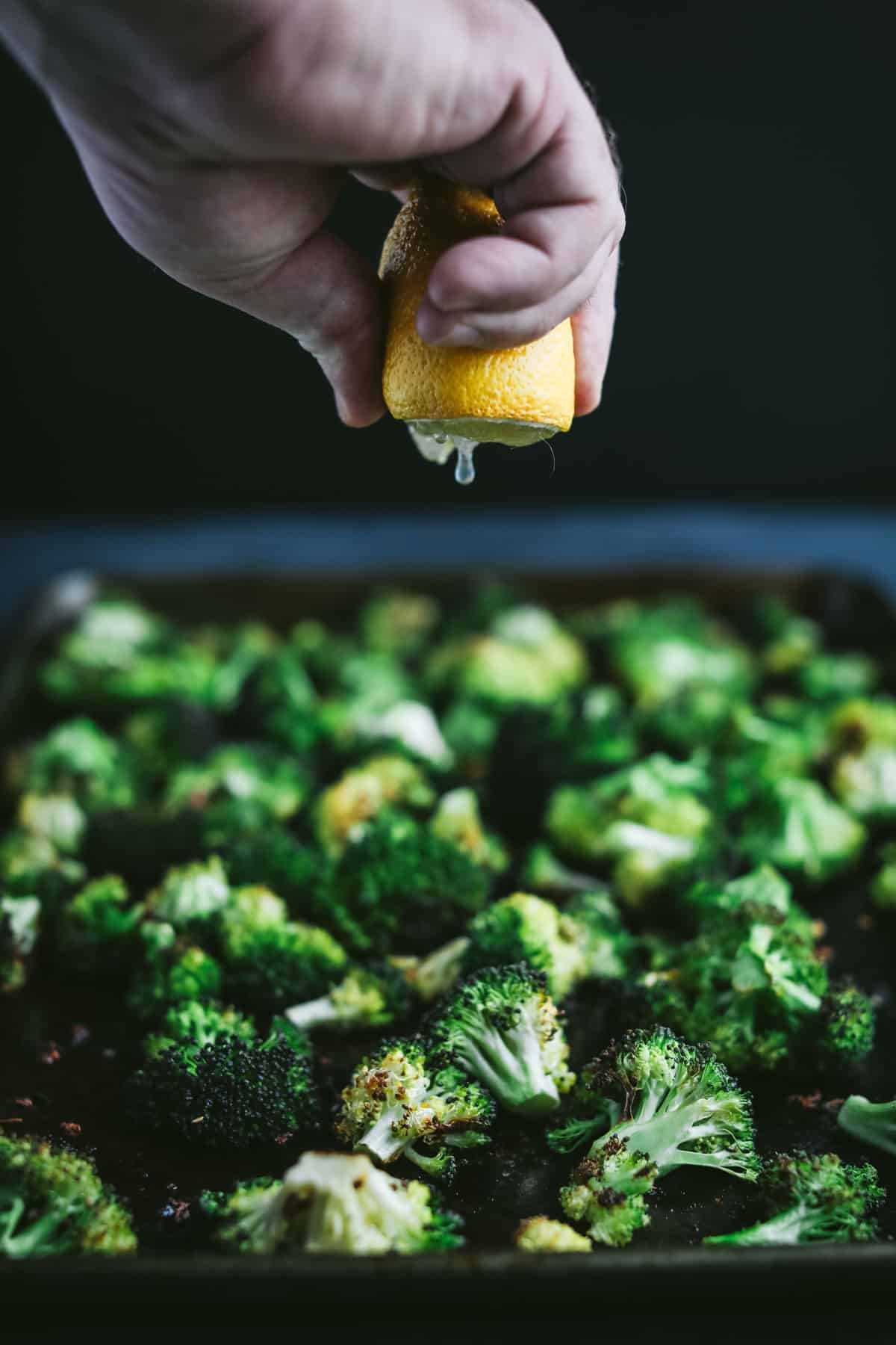 Lemon being squeezed on broccoli