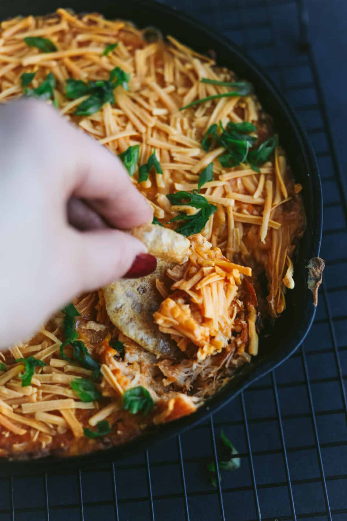 Buffalo chicken dip being dipped with a pork rind