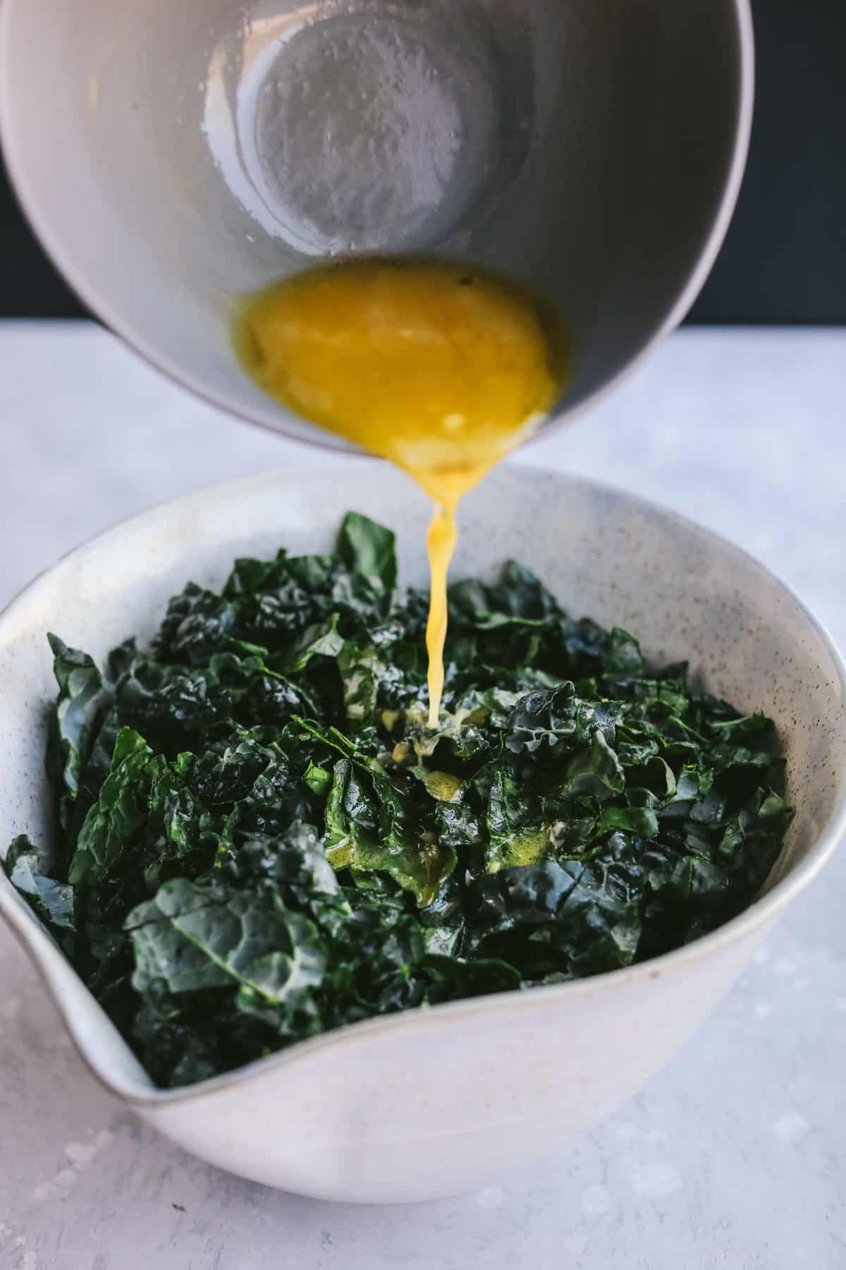 dressing being poured on kale